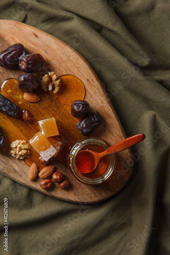 Set for Tea drinking. Various sweets, nuts and honey for tea on a wooden cutting board. Walnuts, almonds, hazelnuts, dates, rahatlukum, honey, dried fruits. Natural sweets. Top view. photo