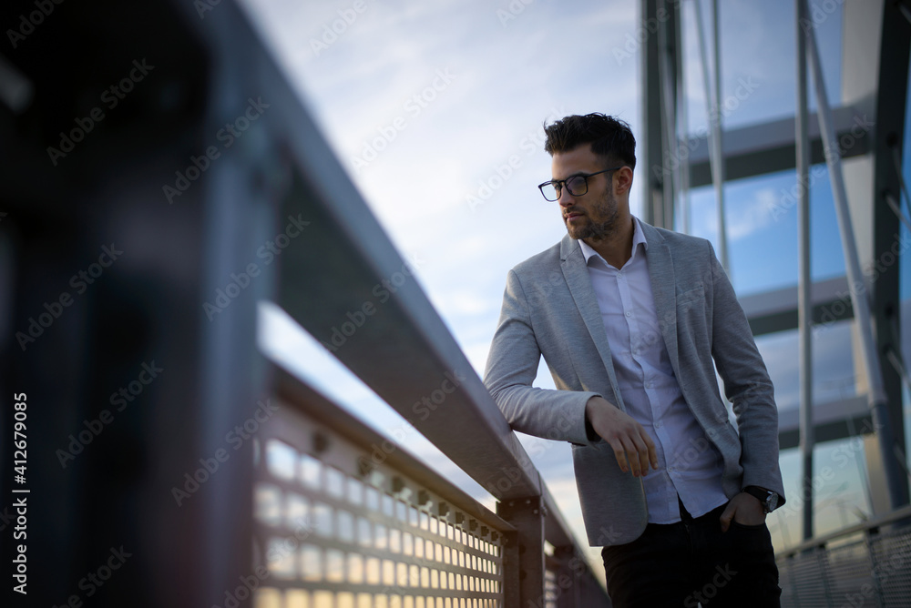 Pensive young businessperson at sunset. Yuppie thinking at the end of the work day Pensive young businessperson at sunset. Yuppie thinking at the end of the work day