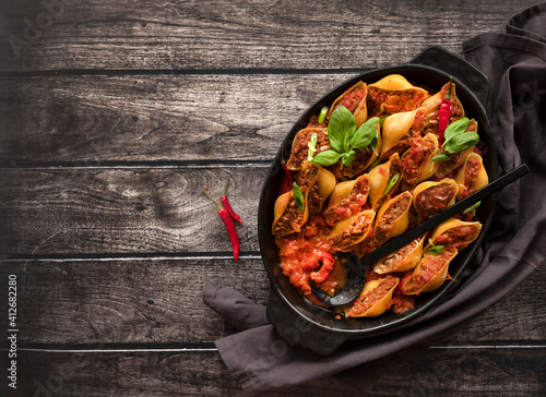 Conchiglioni stuffed with minced meat and baked in tomato sauce, close-up, top view. Copy Space photo