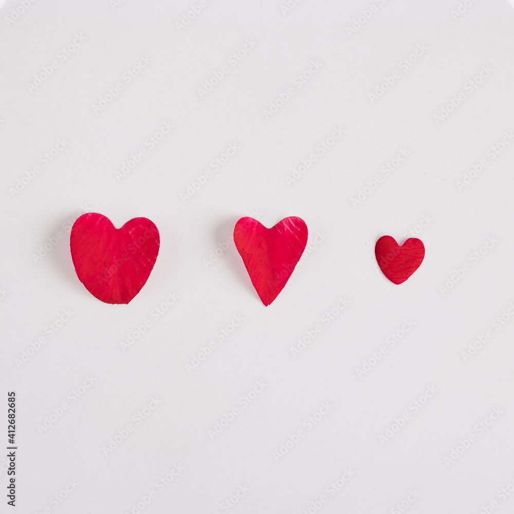 Red hearts made of red rose petals on a white background. Minimal love concept. Mother's day or Valentines idea.
