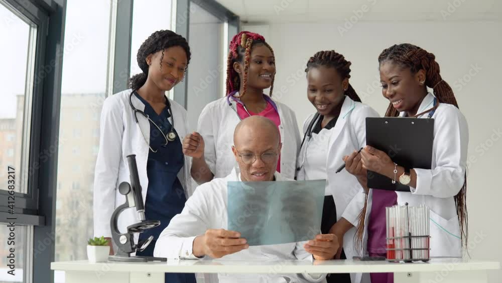 Five african american doctors man and women examine an x-ray while standing at a table