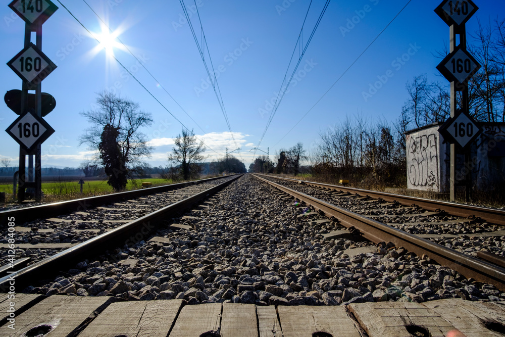 Fototapeta premium Railway crossing wood path straight rails perspective on a solid blue sky