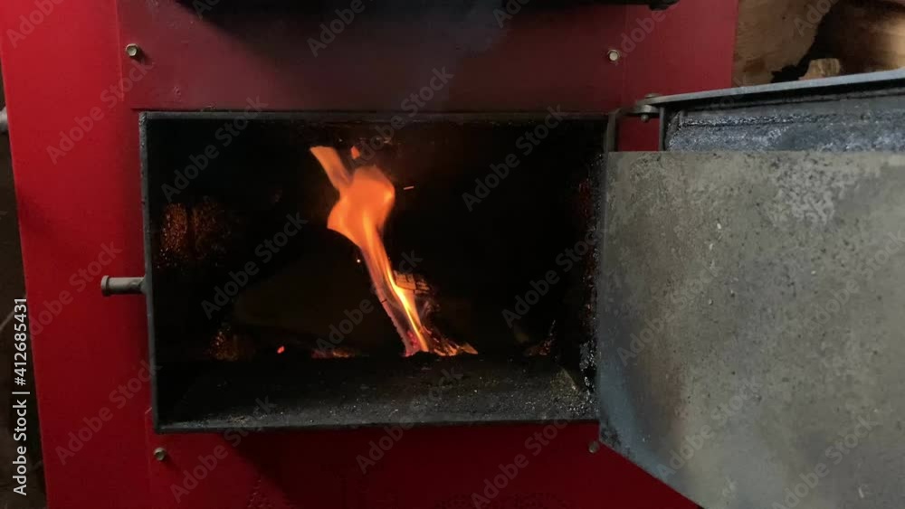 Wood fired Boiler. Heating house in Winter. Burning firewood. Man opens metal doors to add wood. Wood fired Boiler. Heating house in Winter. Burning firewood. Man opens metal doors to add wood.