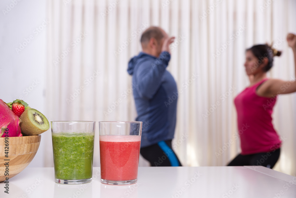 Smoothies and fruits in focus and people exercising in the background out of focus Smoothies and fruits in focus and people exercising in the background out of focus