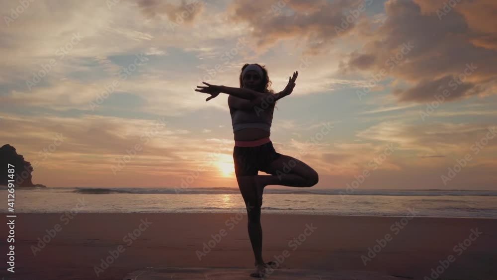 A girl practices yoga on the beach at sunset A girl practices yoga on the beach at sunset