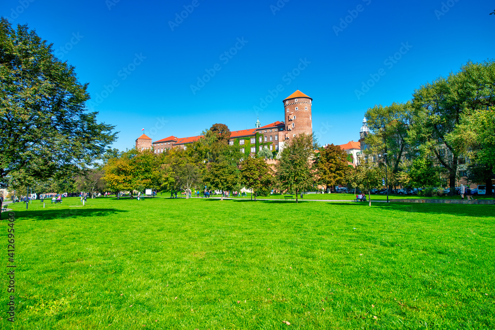 KRAKOW, POLAND - OCTOBER 1, 2017: Tourists visit a beautiful city park with medieval landmarks on a sunny day