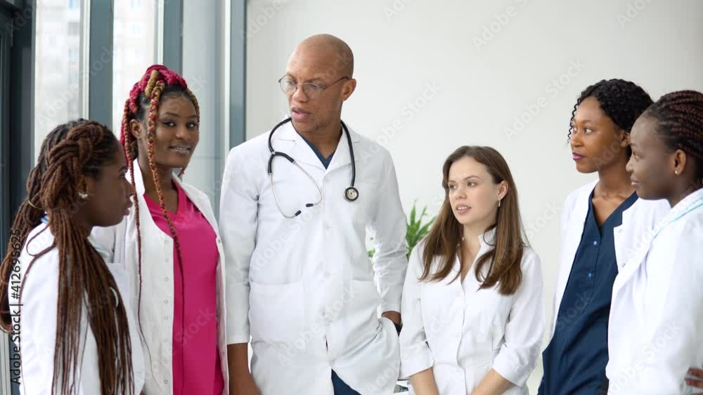 A team of doctors, including international man and women, have a business conversation while standing in a clinic A team of doctors, including international man and women, have a business conversation while standing in a clinic