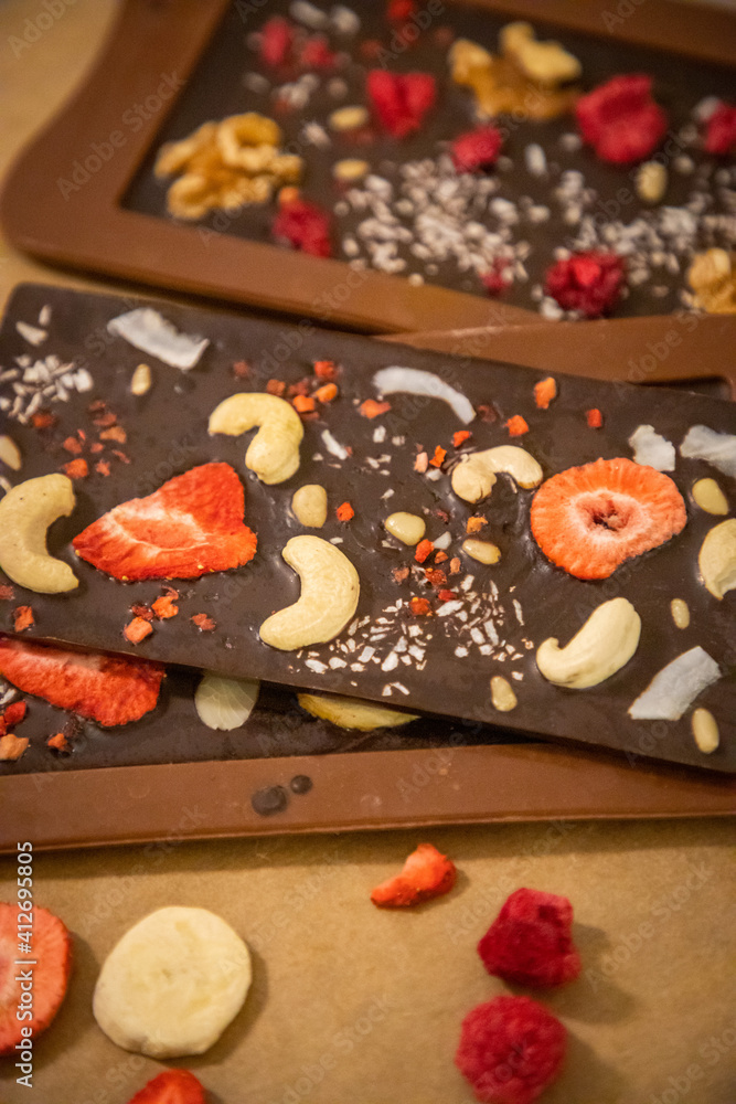 Handmade chocolate with fresh and dried fruits on light paper background in rustic style