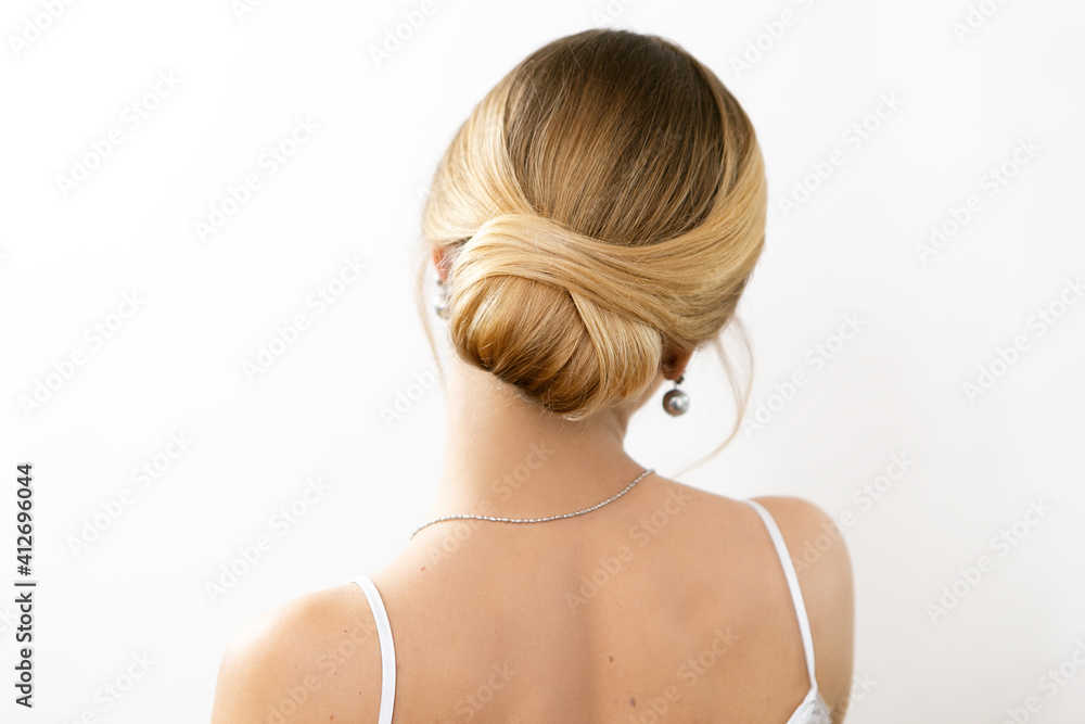 Hair stylist makes a beautiful hairstyle for a girl on a light background Hair stylist makes a beautiful hairstyle for a girl on a light background