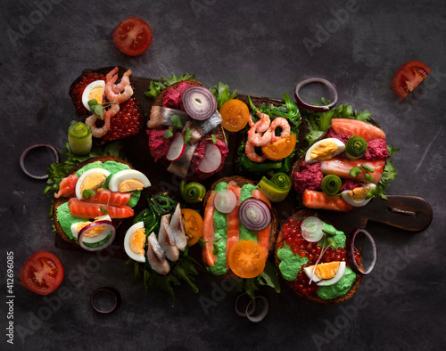 Smorrebrod, traditional Danish open sandwiches, dark rye bread with various fillings, black background, top view