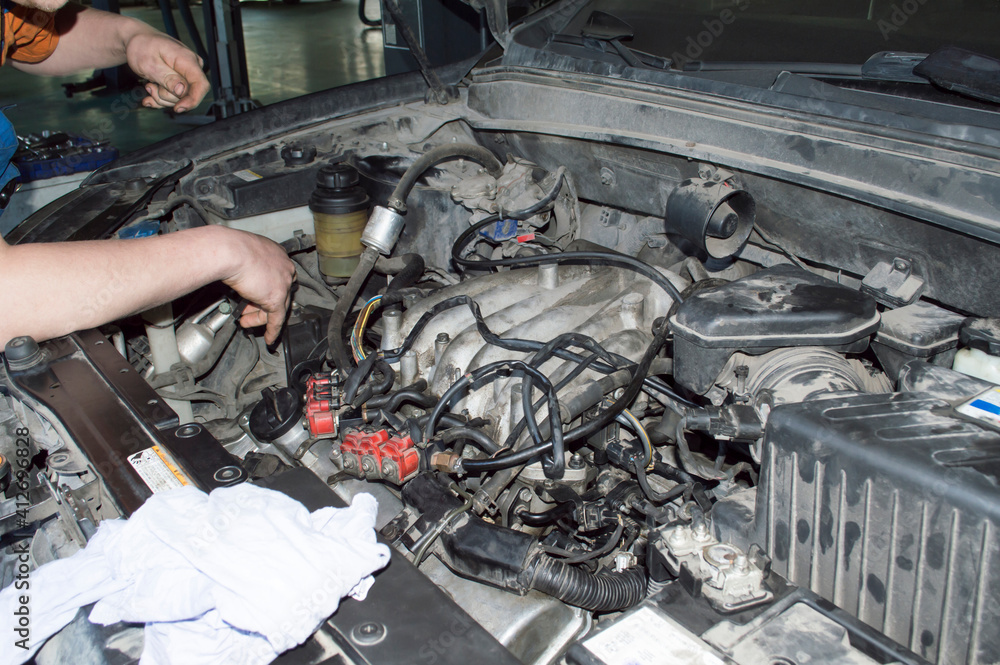 The mechanic checks under the hood of the car The mechanic checks under the hood of the car