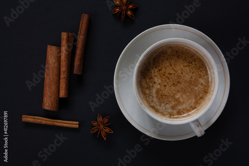 A mug of aromatic coffee with cinnamon sticks on a dark background. 