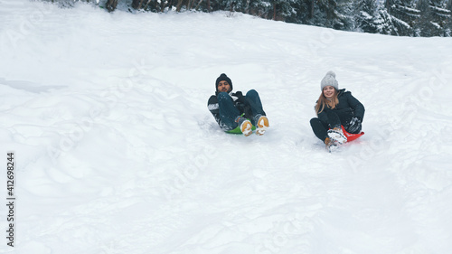 Happy young multiracial couple sliding on snow. Winter sports. High quality photo
