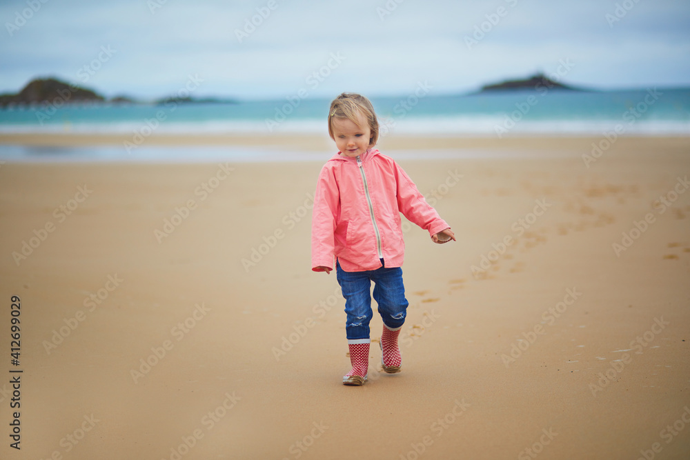 Adorable toddler girl on the sand beach at Atlantic coast of Brittany, France Adorable toddler girl on the sand beach at Atlantic coast of Brittany, France
