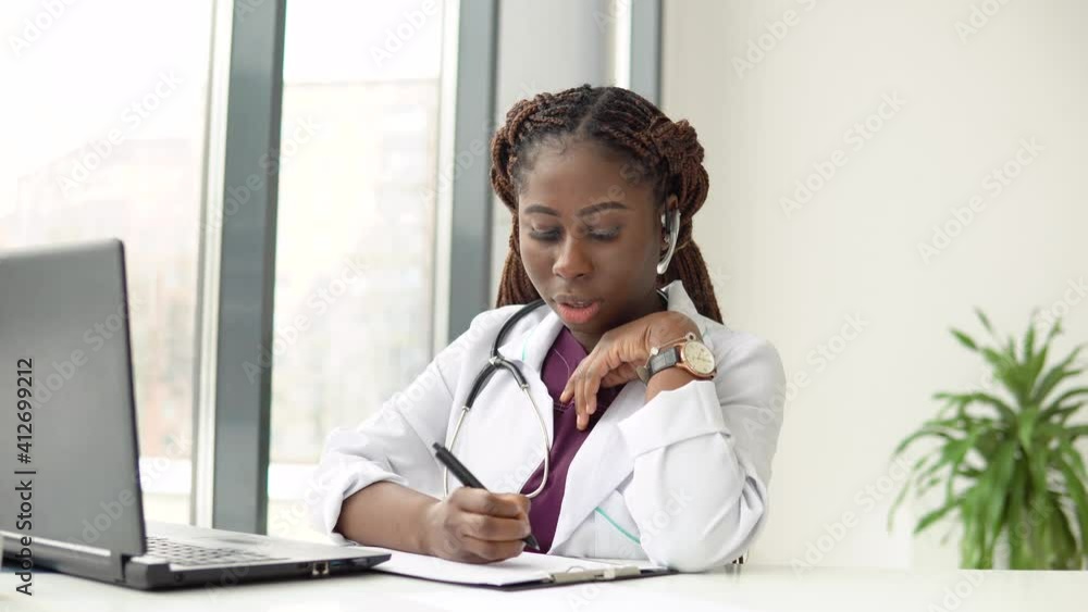 Young african american woman doctor with headset having chat or consultation on laptop Young african american woman doctor with headset having chat or consultation on laptop