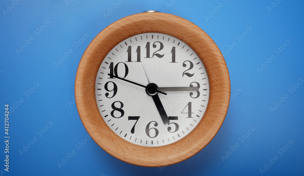 Wooden round clock on blue background.