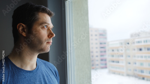 Thoughtful handsome man looks out the window.