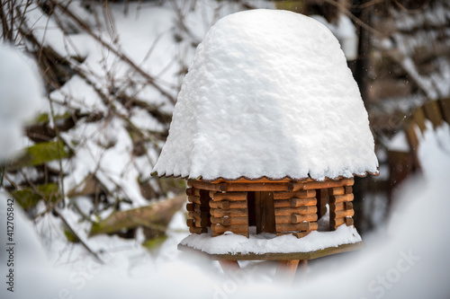 Hölzernes Vogelhaus mit hoher Schneedecke auf dem Dach