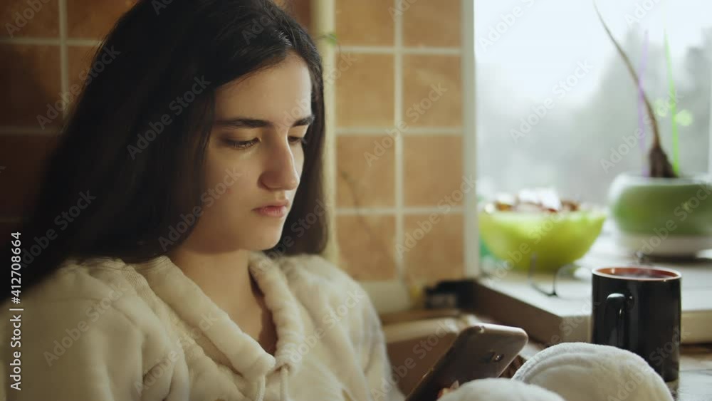 Brunette girl sitting at home in the kitchen with mobile phone, camera tracking Brunette girl sitting at home in the kitchen with mobile phone, camera tracking