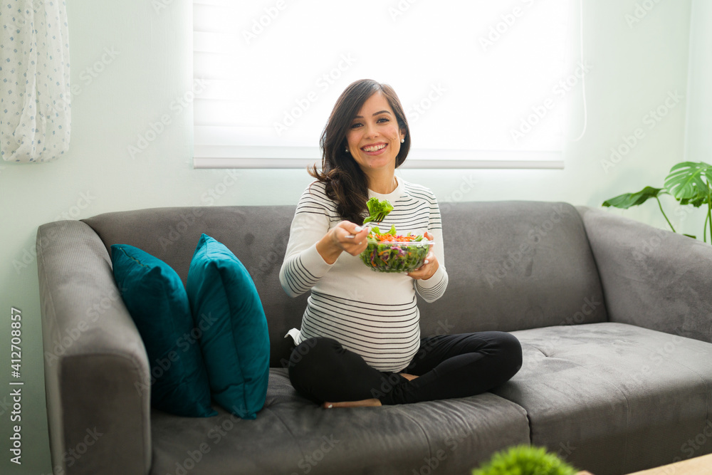 Portrait of a pregnant woman smiling and eating a salad Portrait of a pregnant woman smiling and eating a salad