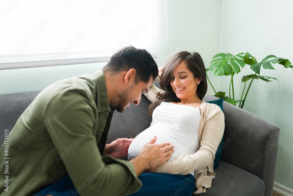 Husband touching and talking to the belly of his pregnant wife Husband touching and talking to the belly of his pregnant wife