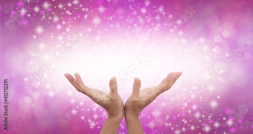 Connecting to High Frequency Magenta Universal Healing Energy - female cupped hands reaching up into a beautiful white light against a pink energy field background with sparkles and white light 
