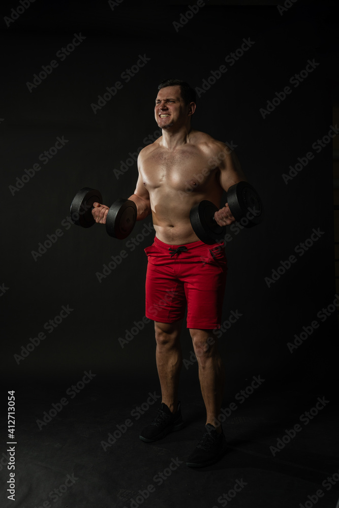 Fitness man presses dumbbells in red panties confident caucasian smart, happy. Happiness model, dumbbells cool background black bodybuilder Fitness man presses dumbbells in red panties confident caucasian smart, happy. Happiness model, dumbbells cool background black bodybuilder