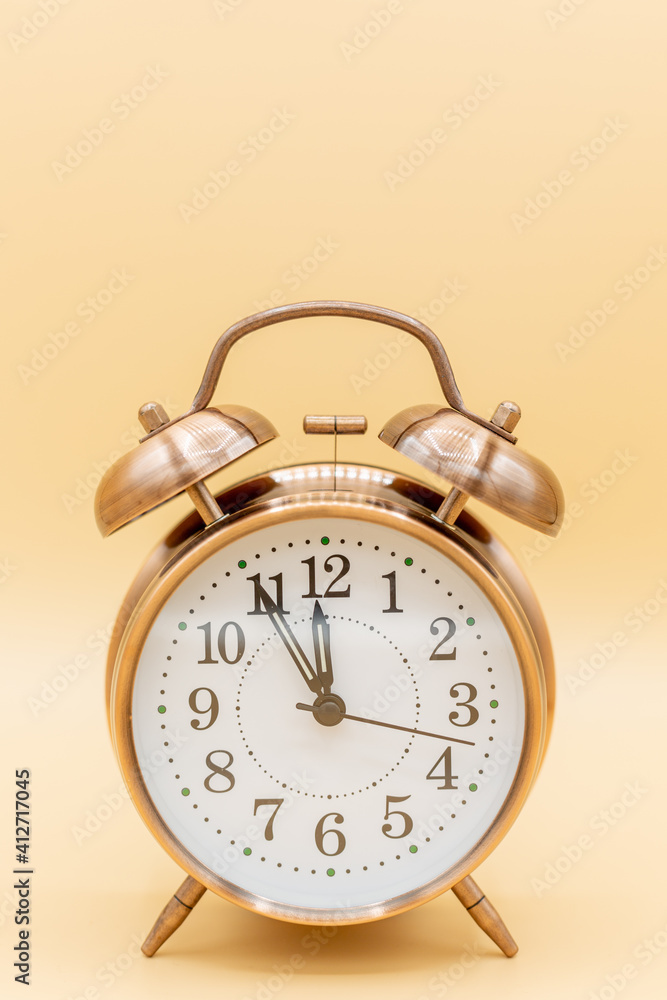 old clock with time five to twelve, symbolilize time shortness, bottleneck and hurry with yellow background old clock with time five to twelve, symbolilize time shortness, bottleneck and hurry with yellow background