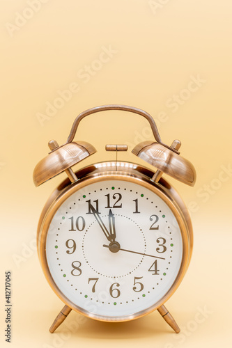 old clock with time five to twelve, symbolilize time shortness, bottleneck and hurry with yellow background