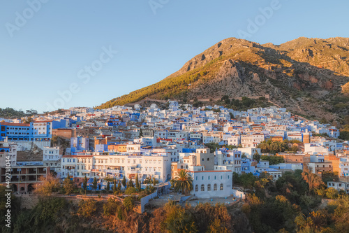 A scenic sunset or sunrise cityscape view over Chefchaouen, Morocco, known as the Blue Pearl with its shades of blue on the town's historic buildings.