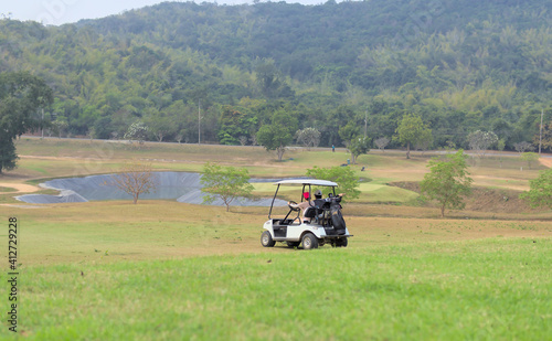 Golfers riding on a golf cart inside a picturesque golf course.