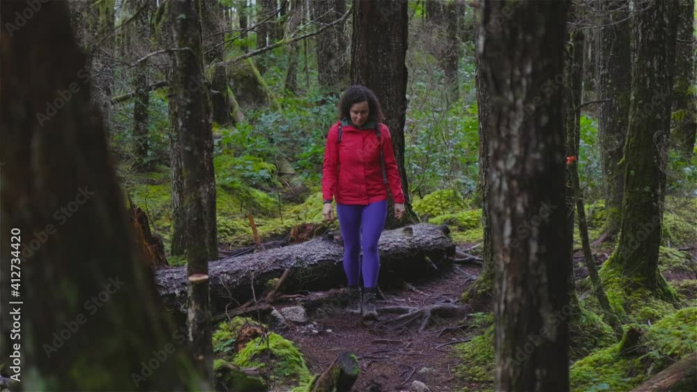 Girl Hiking on a Path in the Rain Forest during a rainy Winter Season. Squamish, North of Vancouver, British Columbia, Canada. Slow motion Girl Hiking on a Path in the Rain Forest during a rainy Winter Season. Squamish, North of Vancouver, British Columbia, Canada. Slow motion