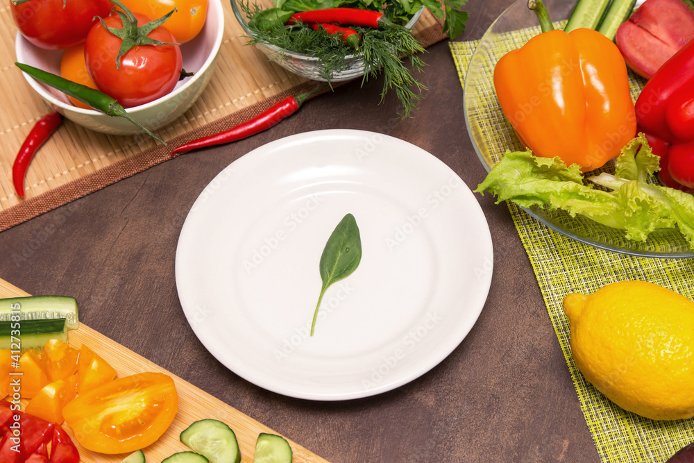 Different vegetables for cooking and one spinach green leaf on white plate. Diet, fasting, vegan, vegetarian, healthy food concept Different vegetables for cooking and one spinach green leaf on white plate. Diet, fasting, vegan, vegetarian, healthy food concept