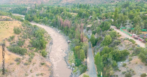 Aerial view of Maipo River in Cajon del Maipo near of Santiago de Chile with trees and road in the background after golden hour photo