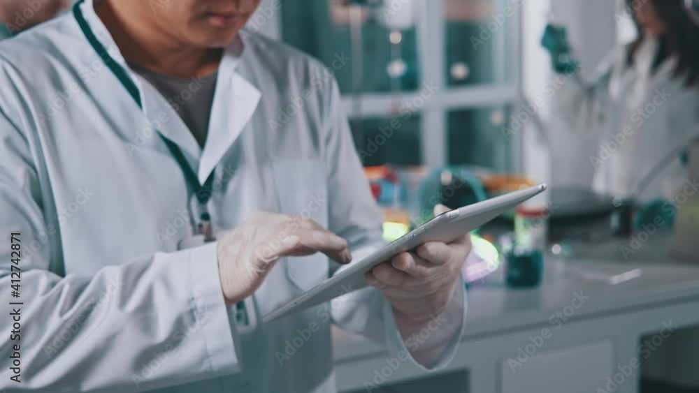 Close up hands man professional expert working in medical laboratory performing research with digital pc tablet computer. Pharmacy, microbiology, industry, biology, technology, doctor. Slow motion Close up hands man professional expert working in medical laboratory performing research with digital pc tablet computer. Pharmacy, microbiology, industry, biology, technology, doctor. Slow motion