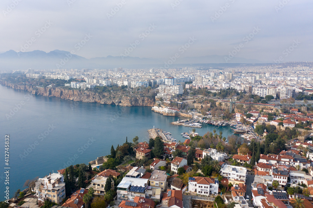 Aerial panoramic view of the Antalya city. Mediterranean sea, and the coast of Antalya. Old town Kaleici, Yacht Marina, mountains and cloudy sky in the background. Aerial drone shooting. TURKEY