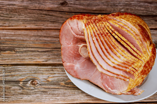 Hickory smoked spiral sliced ham on wooden background.