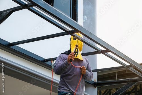 The welder is welding the steel structure to add to the house. © Jirapong