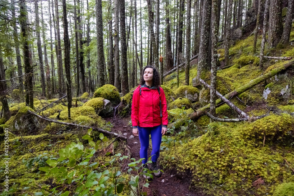 Girl Hiking on a Path in the Rain Forest during a rainy Winter Season. Squamish, North of Vancouver, British Columbia, Canada. Girl Hiking on a Path in the Rain Forest during a rainy Winter Season. Squamish, North of Vancouver, British Columbia, Canada.