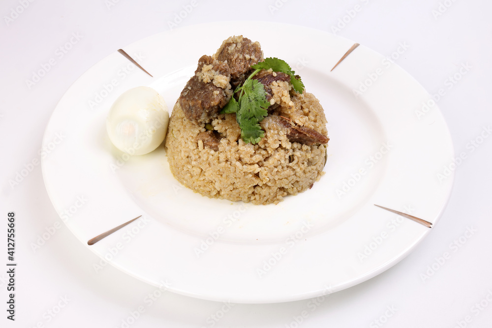 Beef Biryani Tehari cooked in mustered oil with boiled egg coriander leaf garnish on white plate over white background Beef Biryani Tehari cooked in mustered oil with boiled egg coriander leaf garnish on white plate over white background