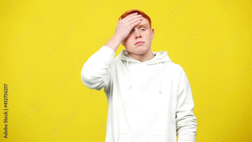Tired young redhead man touching head having migraine and headache. Middle shot portrait of exhausted overwhelmed Caucasian guy posing at yellow background. Health care concept. Tired young redhead man touching head having migraine and headache. Middle shot portrait of exhausted overwhelmed Caucasian guy posing at yellow background. Health care concept.