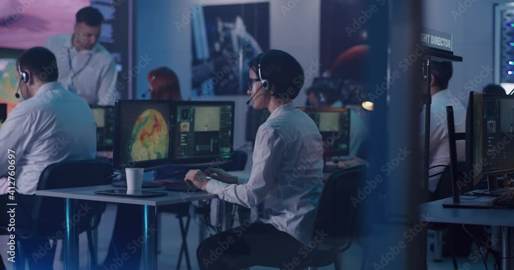 Woman using computer during spacecraft launch near team Woman using computer during spacecraft launch near team