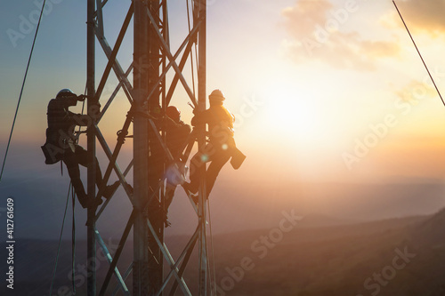 silhouette workers construction of the extension of high-voltage towers on blurred nature background.