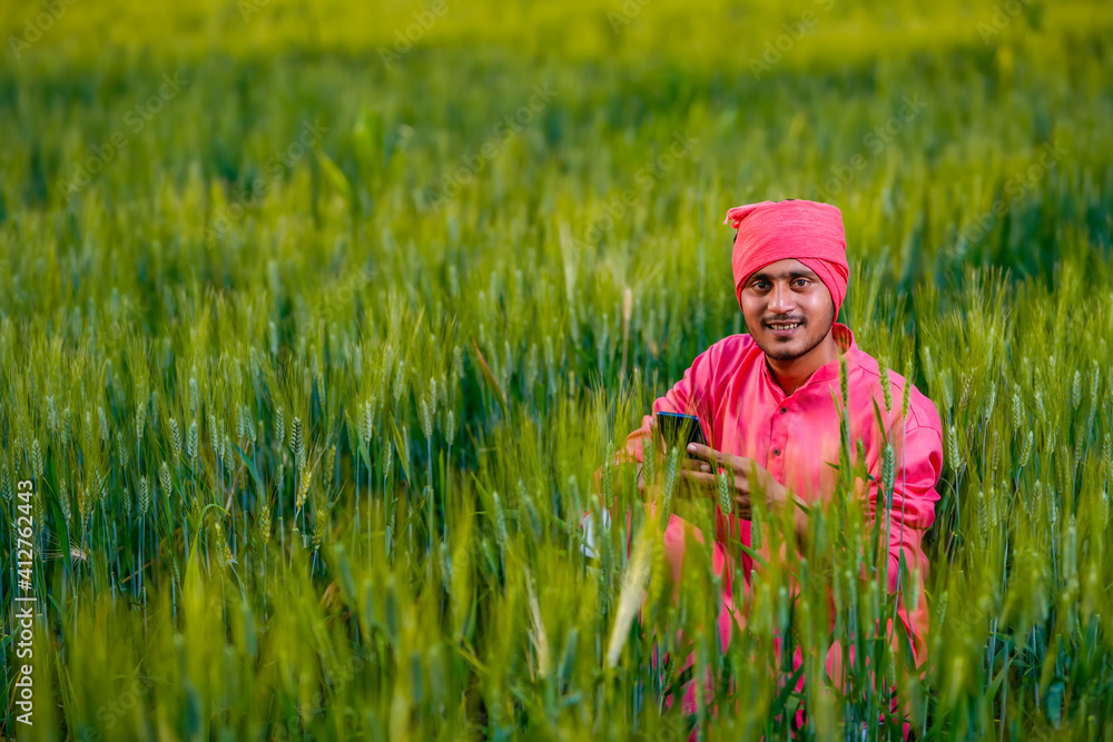 Young indian farmer using smartphone at wheat field Young indian farmer using smartphone at wheat field