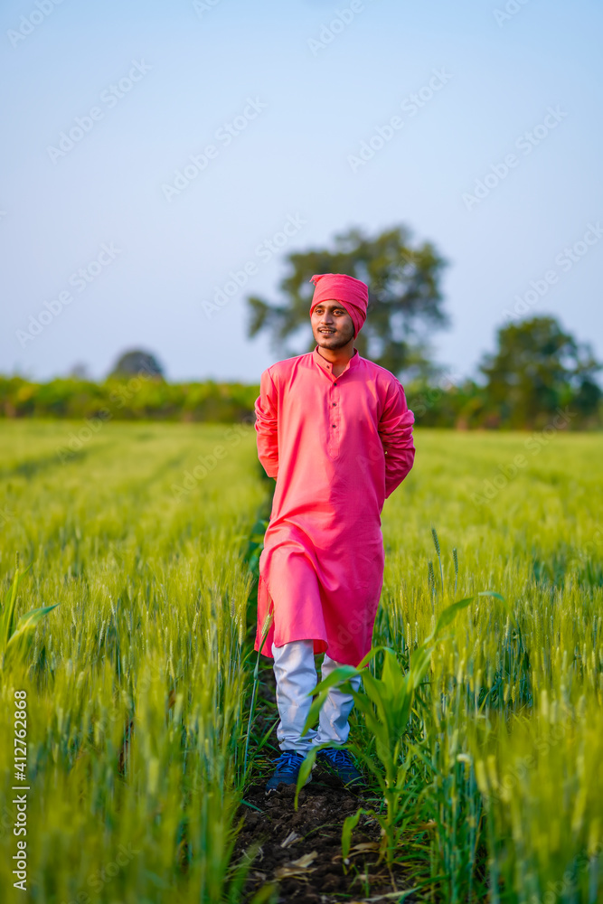 Young indian farmer walking at green wheat field Young indian farmer walking at green wheat field
