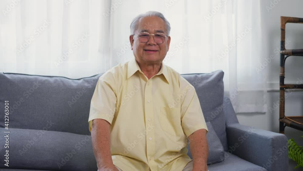 Head shot portrait old man grandfather smile with eyeglasses relaxing looking at camera, Asian happy senior old gray-haired sitting in the living room on sofa alone at home, older people health care Head shot portrait old man grandfather smile with eyeglasses relaxing looking at camera, Asian happy senior old gray-haired sitting in the living room on sofa alone at home, older people health care
