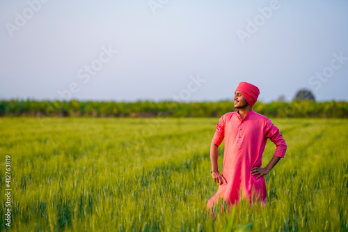 Young indian farmer standing at green wheat field © PRASANNAPIX