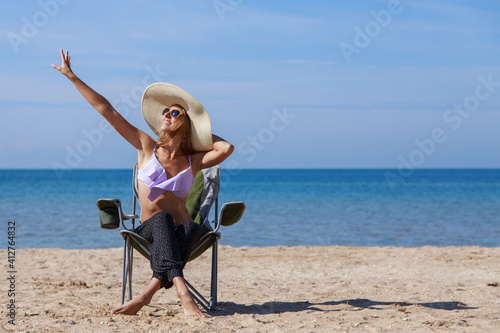 journey to the sea. girl in a bathing suit and hat sunbathing on the beach. tourist sitting on the sand. leisure wear. copy space
