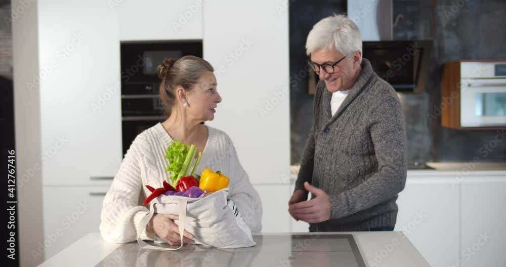 Senior couple unpacking fabric bag with organic food Senior couple unpacking fabric bag with organic food