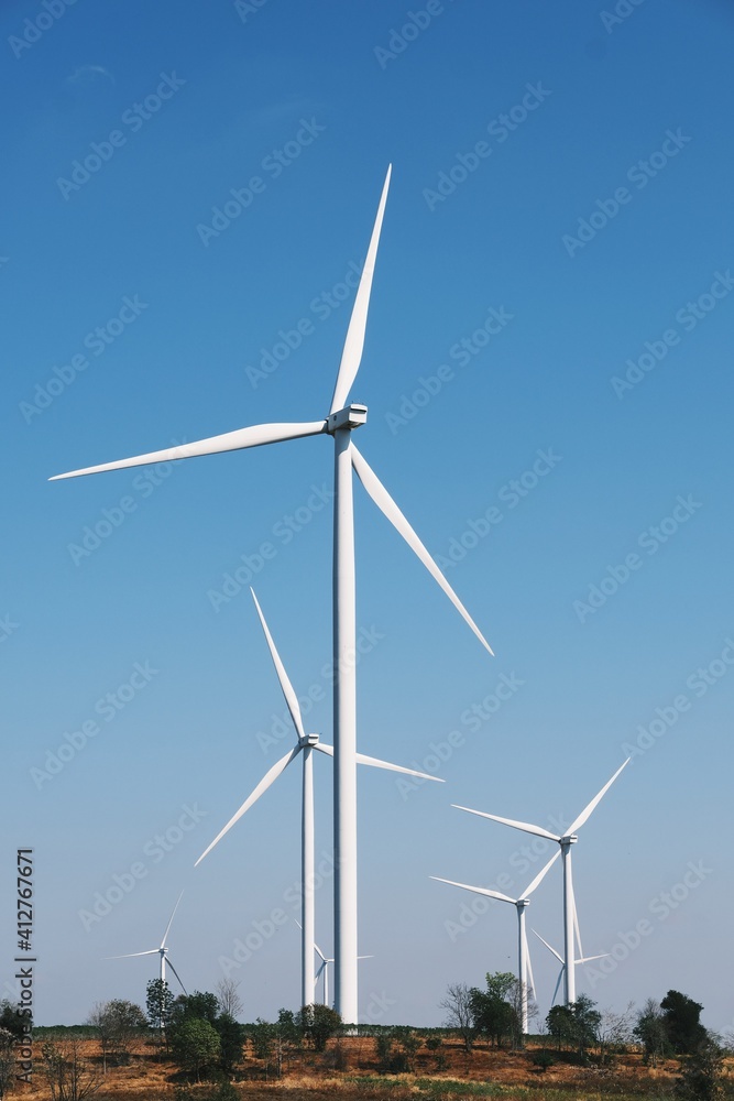 Wind turbines on beautiful sunny summer autumn mountain landsape. Curvy road through mountain Eolic park. Green ecological power energy generation. Wind farm eco field Wind turbines on beautiful sunny summer autumn mountain landsape. Curvy road through mountain Eolic park. Green ecological power energy generation. Wind farm eco field